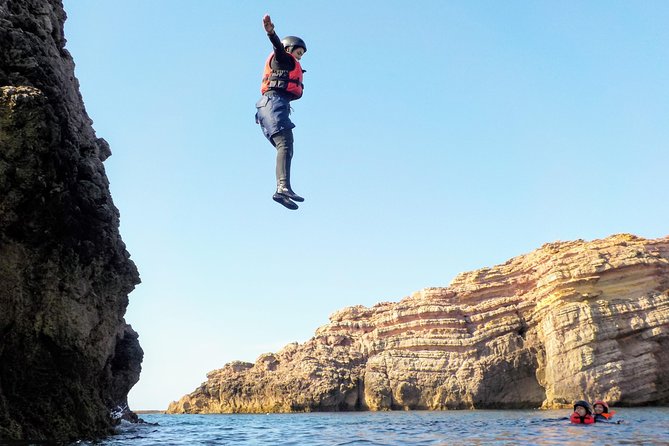 A jumper stepping off a sea cliff into deep water on the Portuguese coast